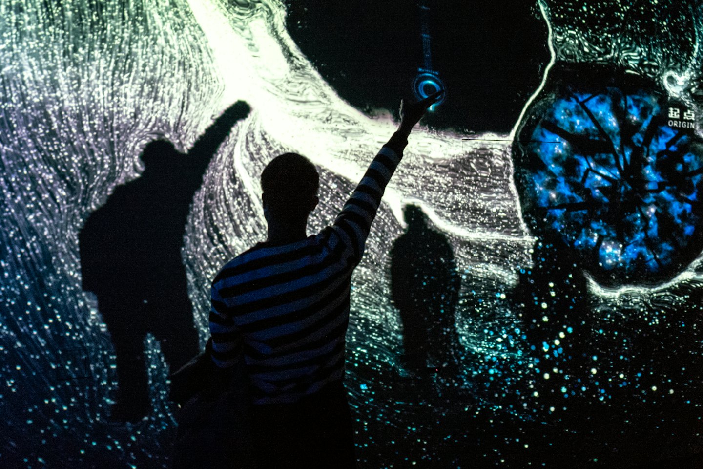 Person reaches towards swirling blue and white digital light patterns.