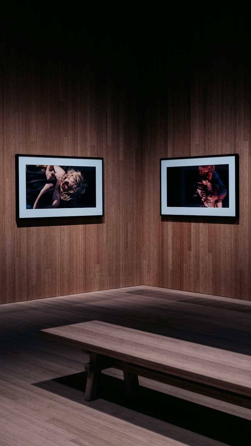 Two framed photographs hang on wooden walls above a bench.