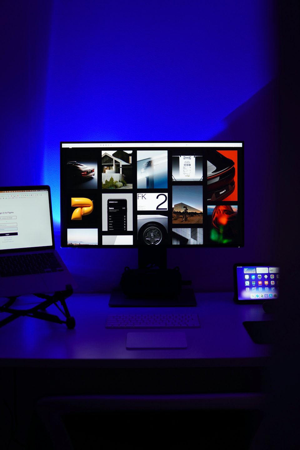 Modern desk setup featuring a monitor, laptop, and tablet.